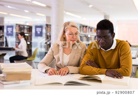 Two adult students studying together in public library Two adult students studying together in public library 92900807