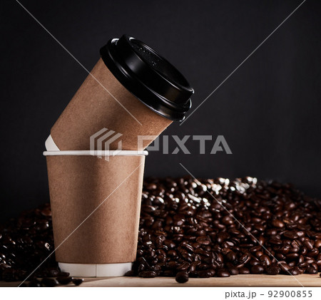 Stay grounded, give warmth and share a latte love. Closeup shot of two paper cups with coffee beans in the background. Stay grounded, give warmth and share a latte love. Closeup shot of two paper cups with coffee beans in the background. 92900855