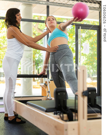 Girl doing exercises in pilates gym with female instructor 92900901
