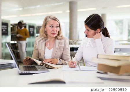 Female teacher working with girl student in university library Female teacher working with girl student in university library 92900959