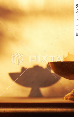 Closeup of lit candle, a symbol of hope, truth or spiritual in brass holder lighting and illuminating dark home room with copy space. Antique decor on a wooden table for aroma, scent and harmony 92902750