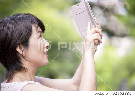 お出かけ中スマホで撮影をするミドル女性 92902836