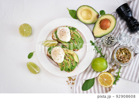 Freshly made poached egg and Avocado toasts on light grey background Freshly made poached egg and Avocado toasts on light grey background 92908608