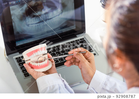 Dentist healthy white tooth model and explorer mirror tool instrument in dentist explaining to patient 92908787