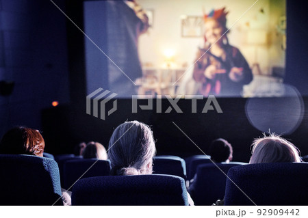 Rear view shot of unrecognizable people spending spare time watching family movie on big screen at cinema Rear view shot of unrecognizable people spending spare time watching family movie on big screen at cinema 92909442
