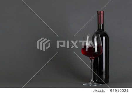 Red wine bottle and glass on a gray background. Wine drinking culture concept. 92910021