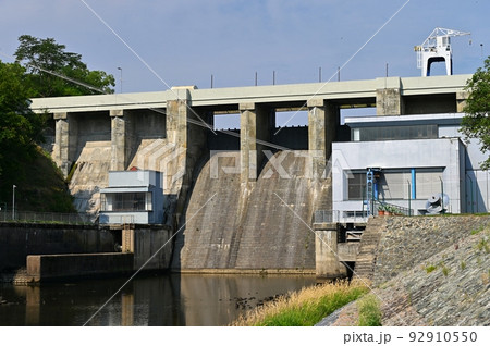 A dam on the Brno Reservoir by the Svratka River with a small power plant. Beautiful sunny summer day in nature. A dam on the Brno Reservoir by the Svratka River with a small power plant. Beautiful sunny summer day in nature. 92910550