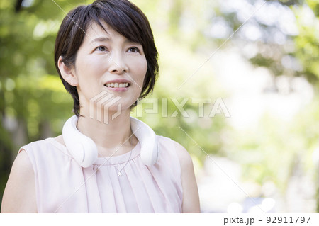 屋外でネッククーラーを使うミドル女性 ネックファン 屋外でネッククーラーを使うミドル女性 ネックファン 92911797