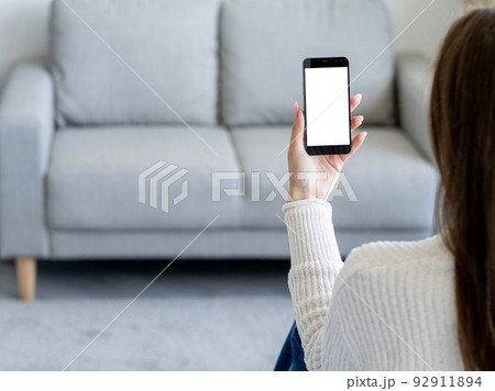 Online communication. Digital mockup. Mobile connection. Unrecognizable woman holding smartphone with blank screen in hands light room interior. Online communication. Digital mockup. Mobile connection. Unrecognizable woman holding smartphone with blank screen in hands light room interior. 92911894