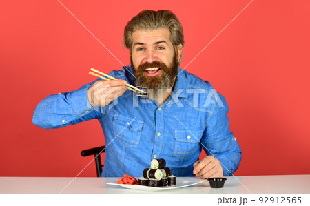 dinner at home. hipster eat sushi with chopsticks. tasty sushi roll. traditional and healthy food in japan. japanese sushi dish. man eating traditional Japanese food with chopsticks dinner at home. hipster eat sushi with chopsticks. tasty sushi roll. traditional and healthy food in japan. japanese sushi dish. man eating traditional Japanese food with chopsticks 92912565