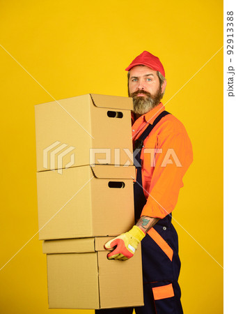 Man wearing boilersuit packing boxes. move to new apartment. bearded loader in uniform. Cardboard boxes - moving to a new house. purchase of new habitation or repair of room Man wearing boilersuit packing boxes. move to new apartment. bearded loader in uniform. Cardboard boxes - moving to a new house. purchase of new habitation or repair of room 92913388