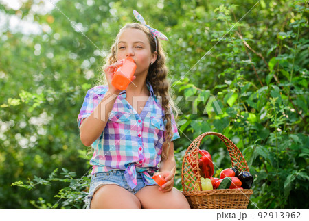 Drink fresh juice. Water balance. Harvest season. Girl adorable child farming. Buy organic food. Kid at farm. Child carry harvest. Sunny day at farm. Little helper concept. Ripe veggies. Family farm 92913962