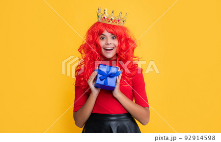 amazed child in diadem with present box on yellow background 92914598
