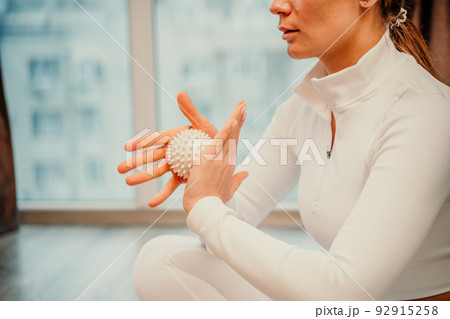 Athletic slim caucasian woman doing thigh self-massage with a massage ball indoors. Self-isolating massage Athletic slim caucasian woman doing thigh self-massage with a massage ball indoors. Self-isolating massage 92915258
