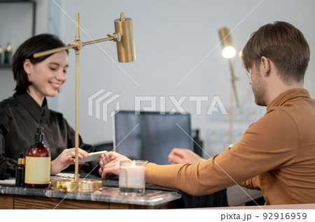 Young man having manicure in a beauty salon 92916959