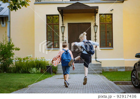 children running to school with backpacks on sunny day. Begining of academic year. Boys by school doorstep 92917436