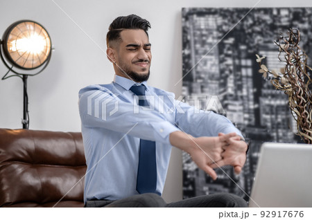 Man with closed eyes stretching in chair 92917676