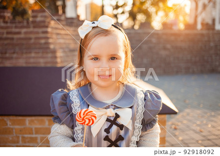 beautiful little girl eats delicious candy, dressed as witch, outdoors, fall, October 31, Happy Halloween. Portrait funny 92918092