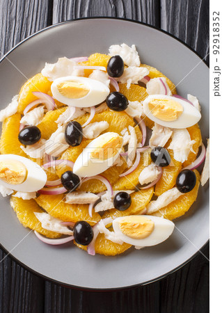 Spanish food Remojon cod, egg, olive, onion and orange salad close-up in a plate. Vertical top view 92918352