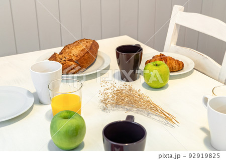 Fresh tasty breakfast served on a white table with croissants, apples and orange juice. Fresh tasty breakfast served on a white table with croissants, apples and orange juice. 92919825