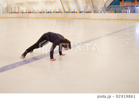 A masked man falls on the ice. The man fell on his skates. Indoor ice rink. A masked man falls on the ice. The man fell on his skates. Indoor ice rink. 92919861