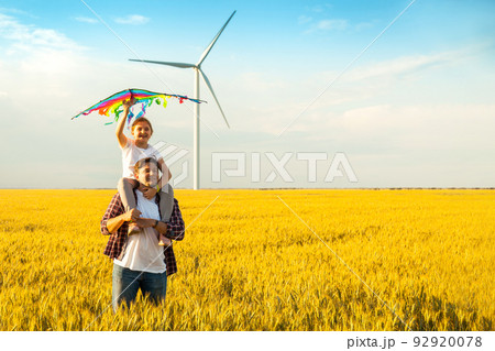 Father and daughter having fun, playing with kite together on the Wheat Field on Bright Summer day Father and daughter having fun, playing with kite together on the Wheat Field on Bright Summer day 92920078