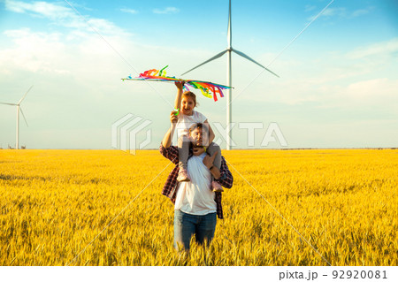 Father and daughter having fun, playing with kite together on the Wheat Field on Bright Summer day 92920081