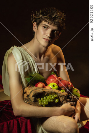 Creative remake of painting boy with a basket of fruit. Young handsome man over dark vintage background. Italian baroque style, art, creativity, vintage Creative remake of painting boy with a basket of fruit. Young handsome man over dark vintage background. Italian baroque style, art, creativity, vintage 92921239