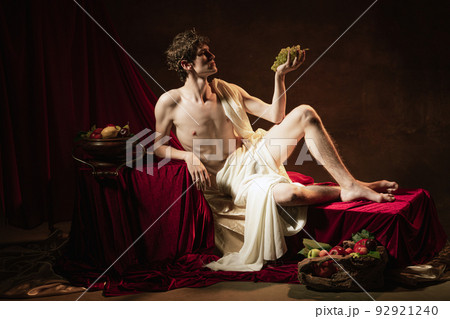 Creative portrait of young handsome man in image of famous historical character, medieval person isolated on dark vintage background. Retro style 92921240