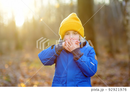 Child warming froze hands during walk in the forest on a cold autumn day. Preschooler boy is having fun while walking through the autumn forest. Family time on nature. Child warming froze hands during walk in the forest on a cold autumn day. Preschooler boy is having fun while walking through the autumn forest. Family time on nature. 92921976