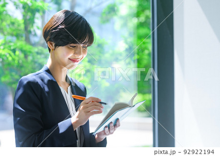 オフィスの廊下でスケジュールを確認するミドルビジネスウーマン撮影協力：LINK FOREST 92922194
