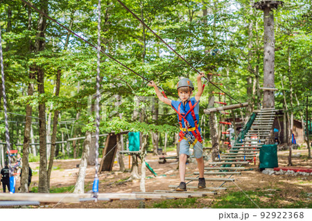 Happy child in a helmet, healthy teenager school boy enjoying activity in a climbing adventure park on a summer day Portrait of a disgruntled girl sitting at a cafe table Happy child in a helmet, healthy teenager school boy enjoying activity in a climbing adventure park on a summer day Portrait of a disgruntled girl sitting at a cafe table 92922368