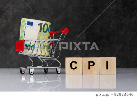 Cash money rolls in shopping trolley, euro banknotes whith wooden blocks with word CPI on white table on dark grey background. CPI, consumer price index symbol. Cash money rolls in shopping trolley, euro banknotes whith wooden blocks with word CPI on white table on dark grey background. CPI, consumer price index symbol. 92923646