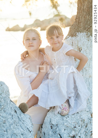 Portrait of cute family. Girls standing near big tree in summer park outdoors. 92925434