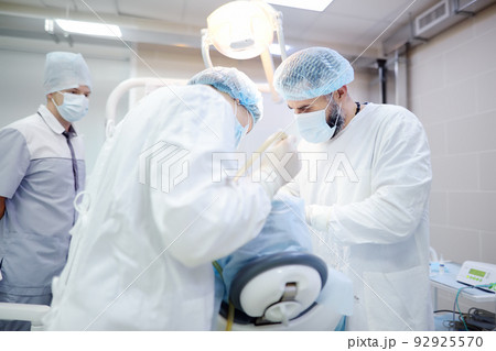 Surgeons and nurse during a dental operation. Anesthetized patient in the operating room. Installation of dental implants in the clinic. 92925570