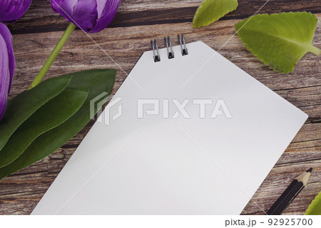 Notepad and pencil with flowers on wooden desk. Copy space. 92925700