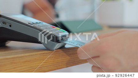 Credit card machine for money transaction. Man hand with credit card swipe through pos terminal and enter pin code. Banking services of electronic money. Financial success and safety. 92926447
