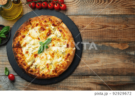 A slice of hot Italian pizza with stretching cheese. Pizza four cheeses with basil. 92929672