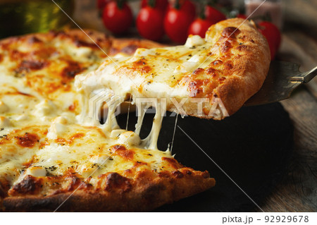 A slice of hot Italian pizza with stretching cheese. Pizza four cheeses with basil. A slice of hot Italian pizza with stretching cheese. Pizza four cheeses with basil. 92929678