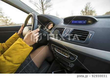 Modern car interior with driver female hands on steering wheel. Safe driving concept. Modern car interior with driver female hands on steering wheel. Safe driving concept. 92930031