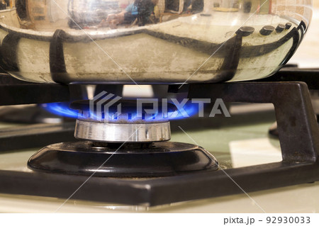 Metal cooking pot standing on kitchen stove with flame. Metal cooking pot standing on kitchen stove with flame. 92930033