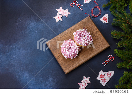 Pink glazed doughnut and marshmallow with Christmas decorations on a wooden cutting board Pink glazed doughnut and marshmallow with Christmas decorations on a wooden cutting board 92930161
