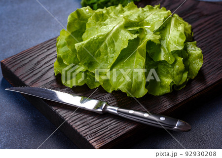 Salad, parsley and dill on a dark cutting board against a blue concrete background Salad, parsley and dill on a dark cutting board against a blue concrete background 92930208