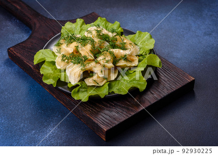 Delicious fresh cooked dumplings with potatoes embellished with greens and lettuce leaves on a dark plate 92930225