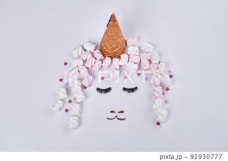 Ice cream cone and marshmallows represent hat and hair. Womans face with eyes closed. 92930777