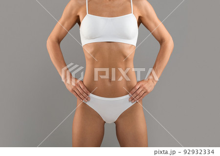 Cropped Shot Of Young Slim Female Body In Underwear Over Grey Background Cropped Shot Of Young Slim Female Body In Underwear Over Grey Background 92932334
