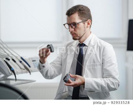 Dentist looking at photopolymer jaw printed on a 3d printer. 92933528