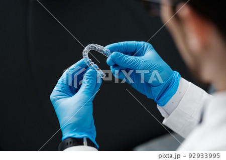 Invisible orthodontics cosmetic aligners in hands of doctor 92933995