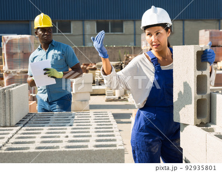 Asian woman worker calls in a colleague for help in a warehouse 92935801