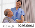 Asian nurse holding an elderly man with a walking stick for physiotherapy. 92936008
